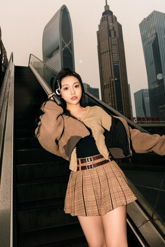 一位年轻女子穿着裙子站在城市中的自动扶梯上