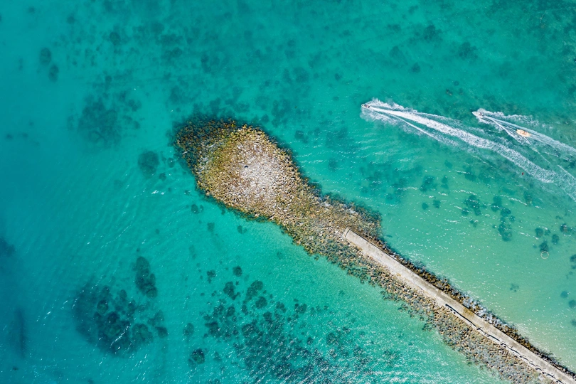 停泊在清澈蓝色海水中的岛屿岸边的船只 aerial