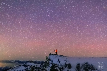 站在雪山上仰望夜空中的星星的人