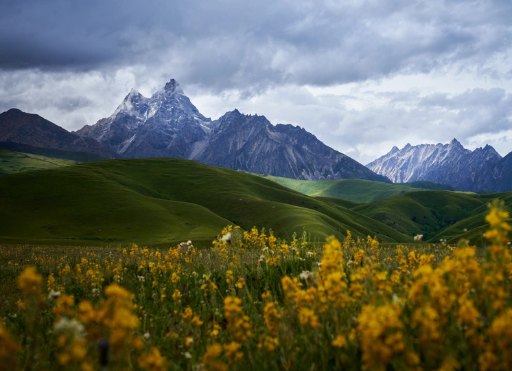 前景为绿山和山谷 远处为被白雪覆盖的山峰。