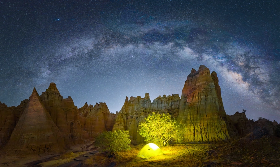 夜晚在山洞上方形成的星空下 帐篷被点亮了。