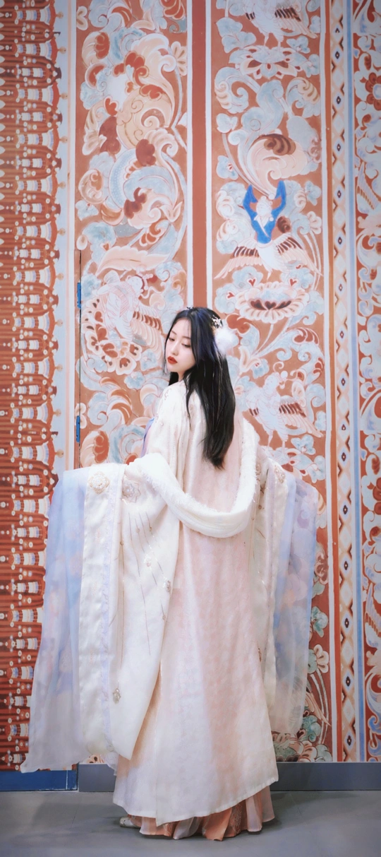 一个穿着白色长袍的模特站在舞台上