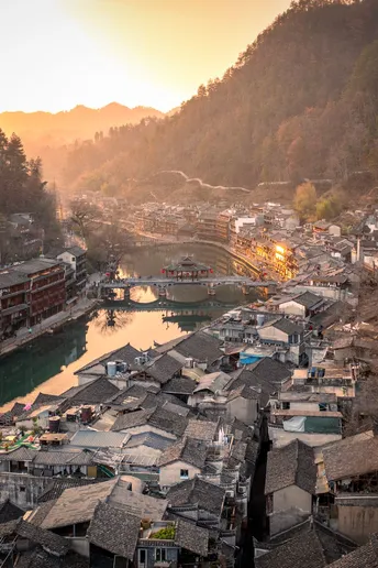 夕阳下俯瞰河流和山峦的小村庄