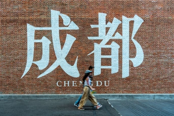 一名女子走在涂鸦墙前的一条街道上