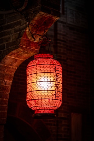 一盏红灯笼挂在一面古老的砖墙上