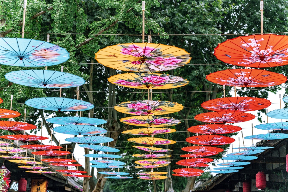 许多不同颜色的雨伞挂在一條街道上。