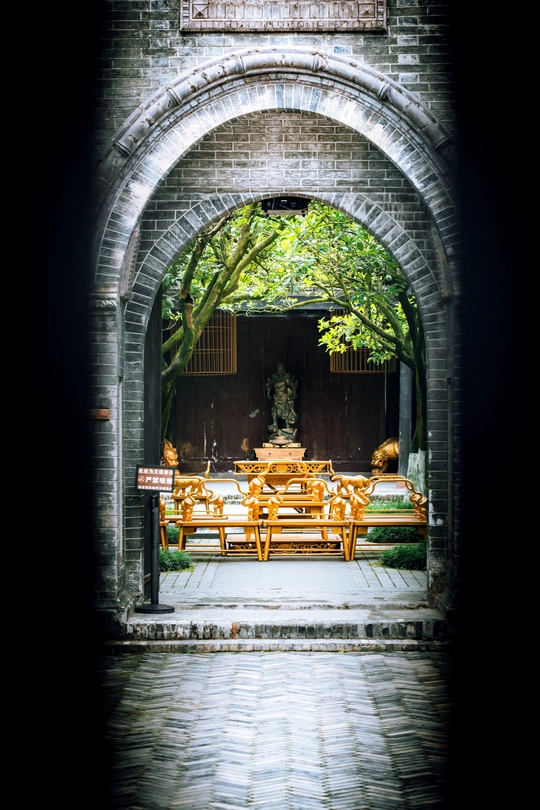 一个有拱门、木制桌椅和树下的庭院