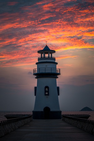 美丽的日落 天空中是红色的 海面上有灯塔。