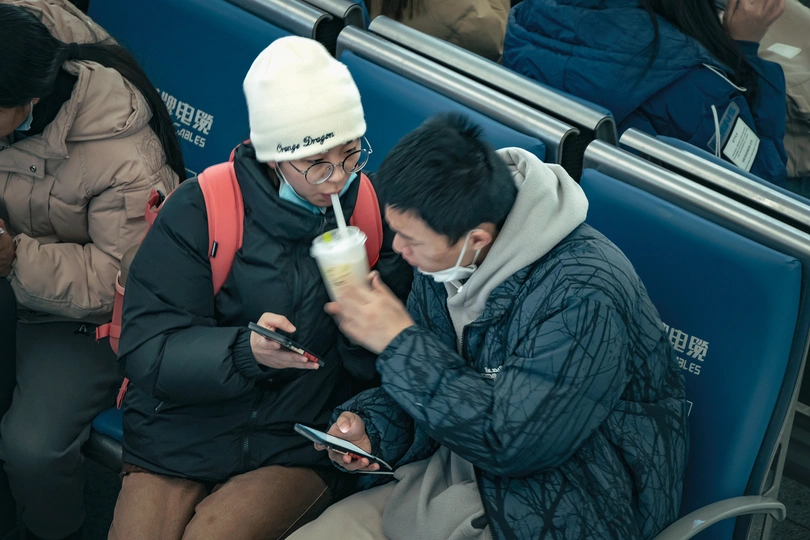 一些人坐在公交车上 看着手机 同时一个男人在吃饭。