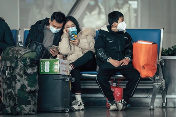 戴口罩的人在机场的长椅上坐着