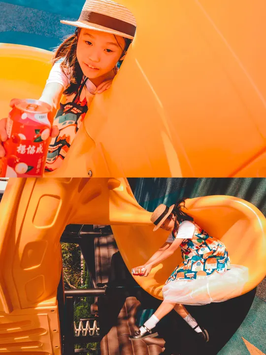 一个戴帽子的小女孩坐在黄色滑梯顶部