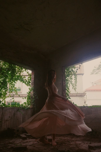 一位穿粉色裙子的女人站在一个带窗户的房间里