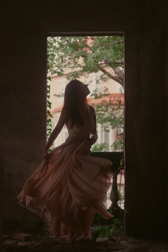 一个穿着漂亮裙子的年轻女子站在一座黑暗的建筑中