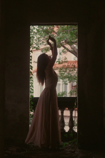 一个穿粉色裙子的女人站在一栋建筑物的门口