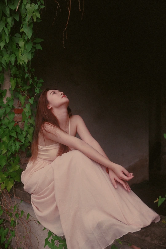 一个美丽的年轻女子穿着白色连衣裙坐在石头边缘