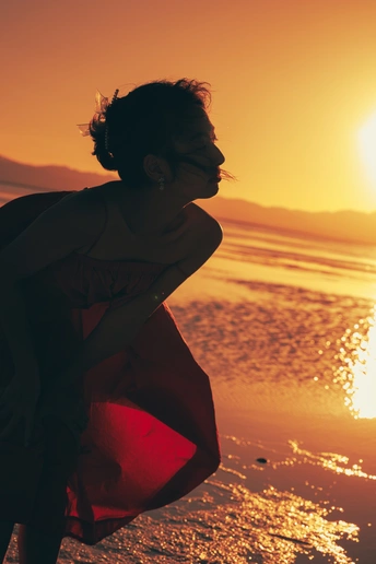 夕阳下海滩上的一个年轻女子抓住太阳