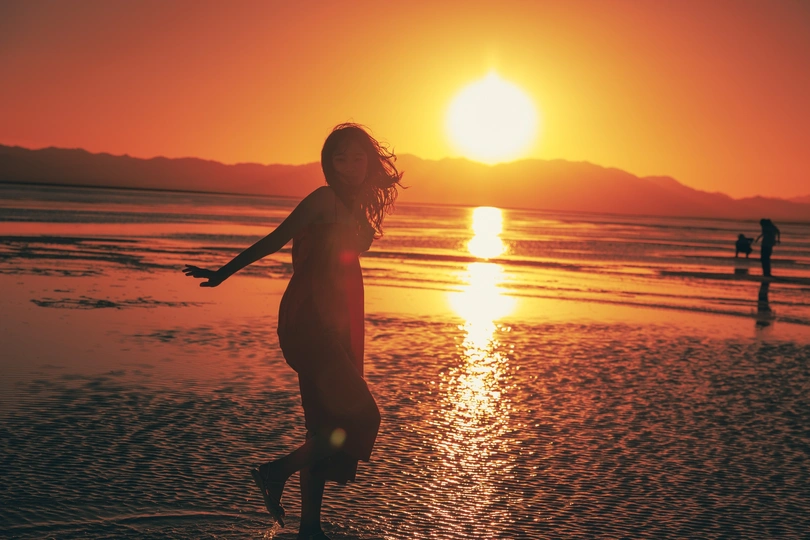 夕阳下 一位年轻女子在海滩上奔跑的剪影