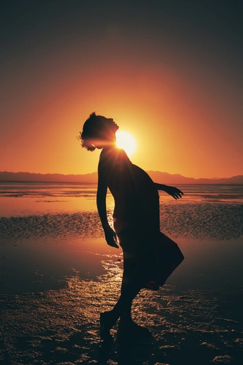 夕阳西下 海面上的沙滩上 一个青年或少女的剪影。