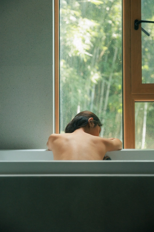 一个人坐在浴缸前的大型窗户前