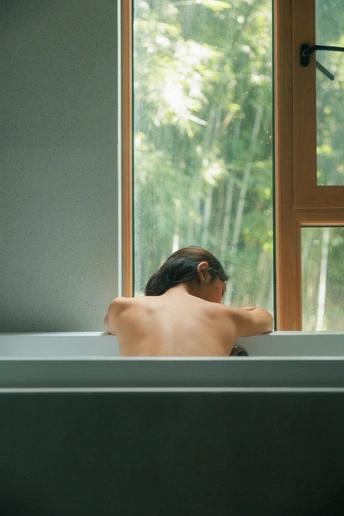 一个人坐在浴缸前的大型窗户前