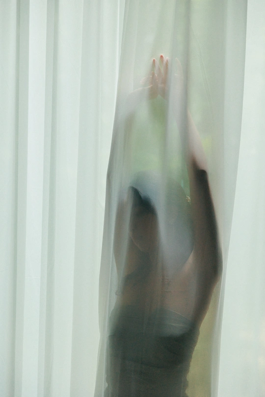 模糊不清的图片 一位站在白色窗帘前的女人