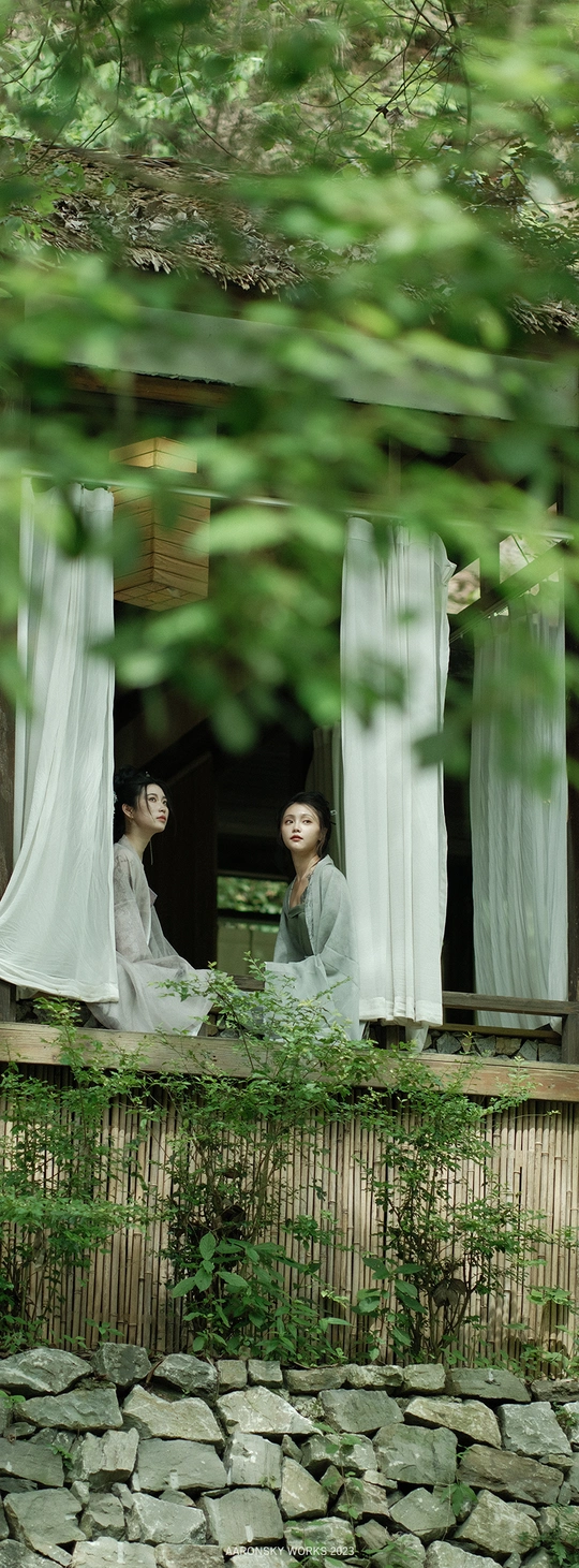 一些女人站在窗前 窗帘是白色的。