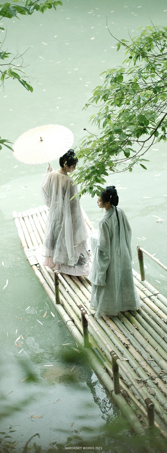 一群穿着和服的女性手持雨伞站在一座木桥上