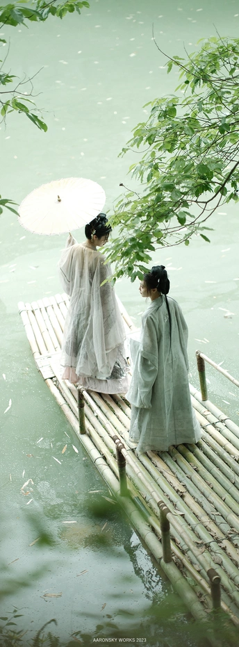 一群穿着和服的女性手持雨伞站在一座木桥上