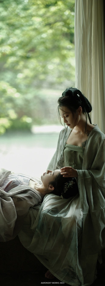 一位怀孕妇女抱着书坐在床上 凝视着窗户。