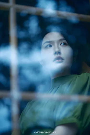 一位女士正在蓝色玻璃窗前向外看