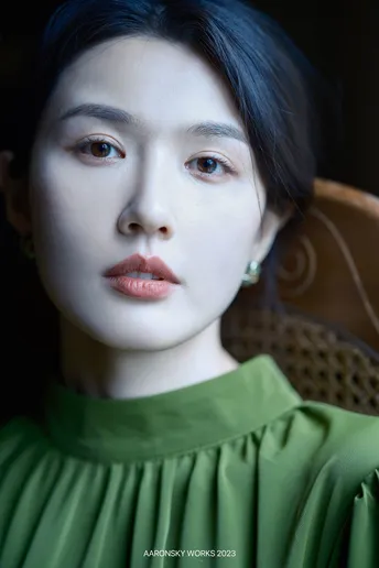 一位穿着绿色连衣裙的年轻女子在昏暗的光线下的人物肖像