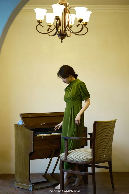 一位穿着绿色连衣裙的女士正在弹钢琴