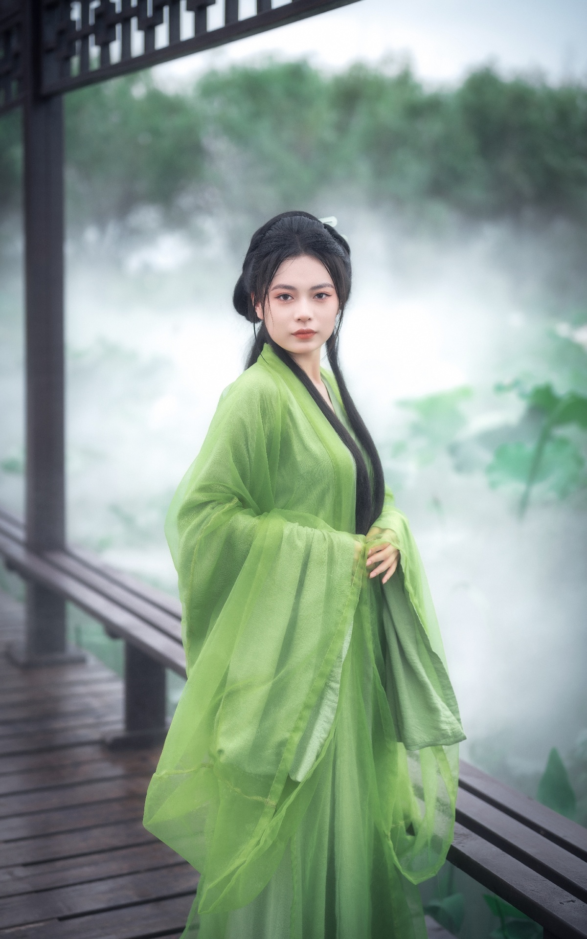 一位美丽的年轻女士穿着一件绿色传统和服站在木桥上