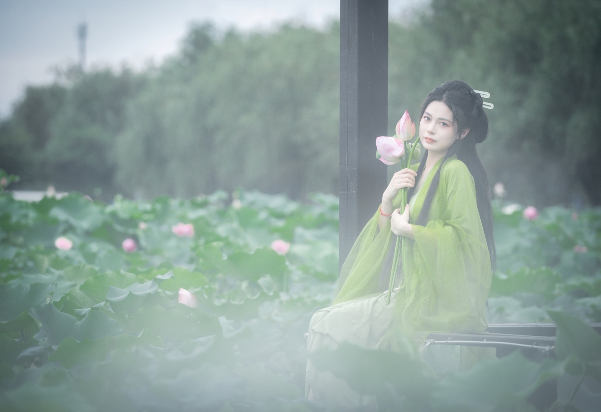 一位穿着中国传统服装的年轻女子 holding a pink flower