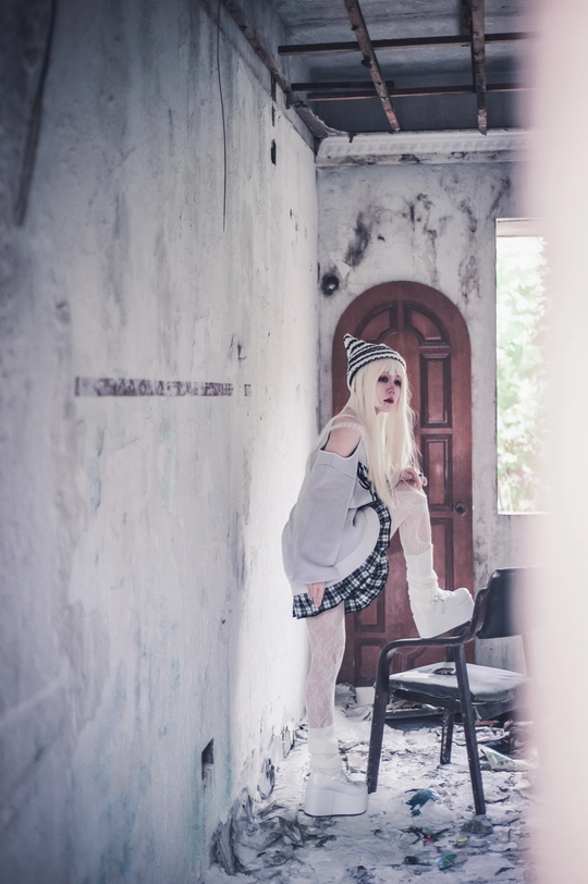 一个年轻女子站在一个白色房间里 房间前面有一把椅子 椅子前面有一扇门。