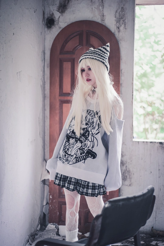 一个戴白色毛衣和帽子 站在椅子旁边的女孩