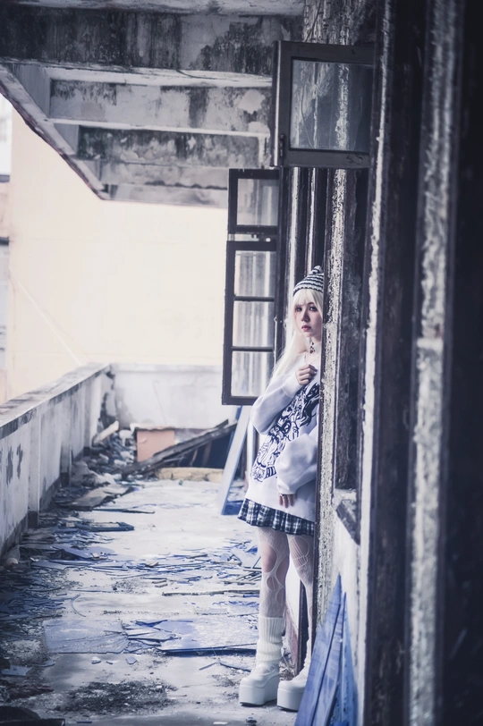 一个年轻女子站在一座废弃的建筑中 手里拿着一把雨伞。