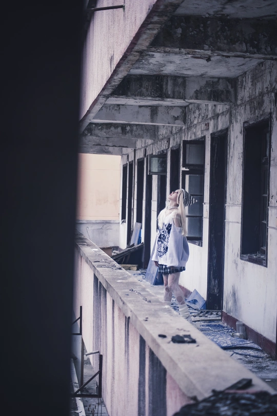 一个年轻女孩站在一座废弃的建筑物上 抬头仰望。