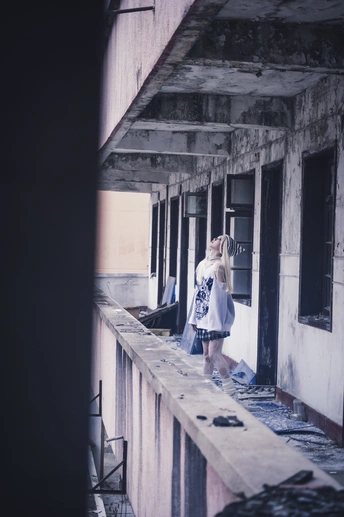 一个年轻女孩站在一座废弃的建筑物上 抬头仰望。