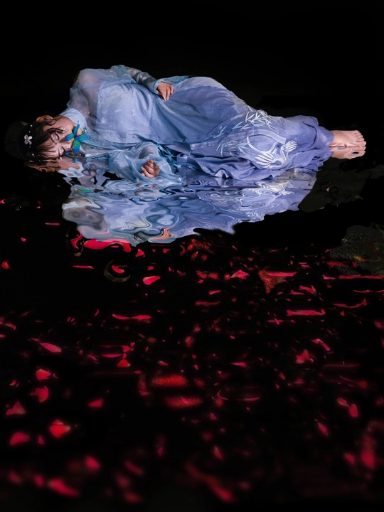一位穿着蓝色连衣裙的女人躺在红色灯光下地板上