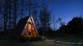 夜晚被星星点亮的森林中的小木屋