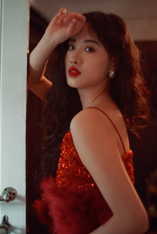 一位穿着红裙子的女人站在门前 对着镜子看。