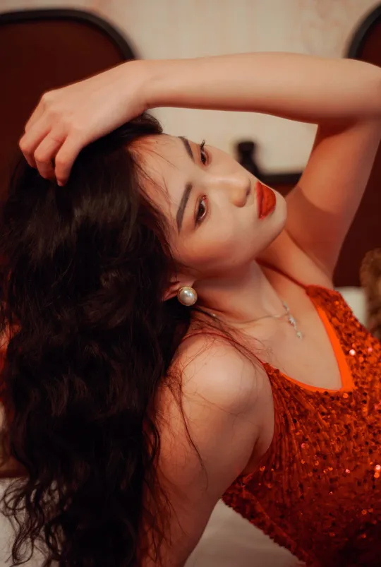 一个穿着橙色连衣裙的年轻女子躺在床上 头发在后面