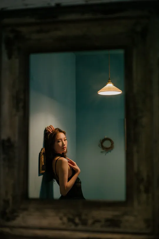 一位穿着连衣裙的年轻女子正在浴室镜前看自己的倒影