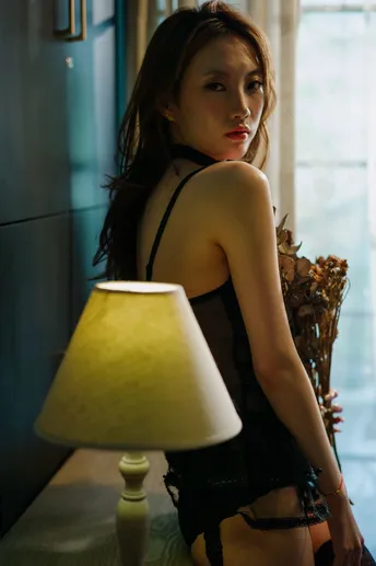 一个穿着黑色连衣裙的年轻女子坐在窗前一张桌子前