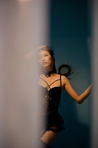 一位穿着黑色连衣裙的年轻女子站在镜子前