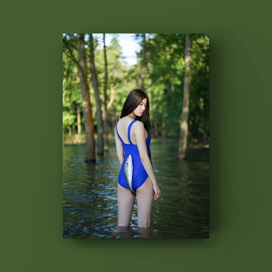 一位年轻女子穿着蓝色泳装站在溪流中的树林中