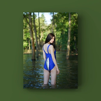 一位年轻女子穿着蓝色泳装站在溪流中的树林中