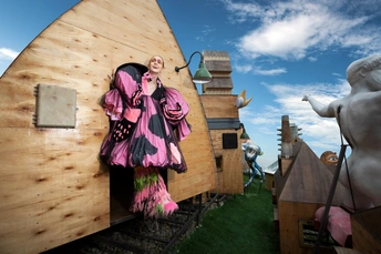 一座女人雕像 站在一所木质房子旁边