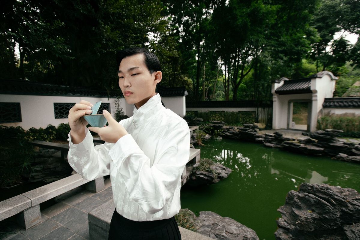 一个穿白衬衫的男子拿着相机在给池塘拍照